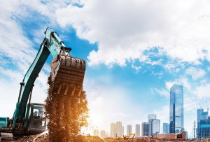 Fotografia de escavadeira jogando terra num terreno em construção, exemplificando a especulação imobiliária