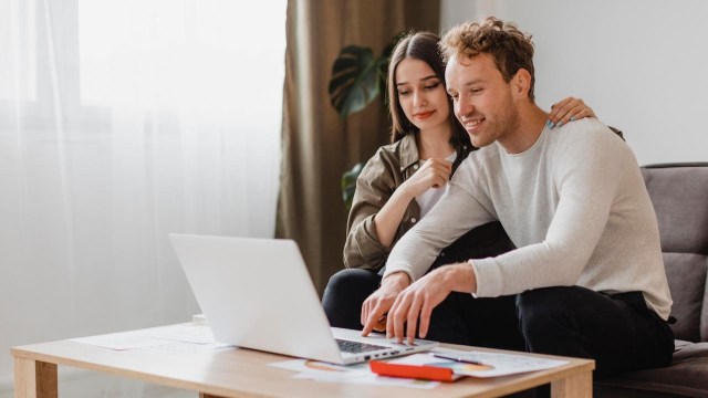 casal sentado no sofá da sala conferindo no laptop como investir em IVVB11