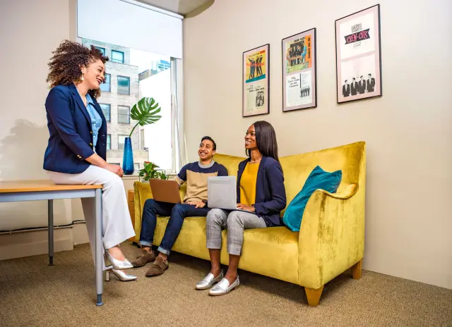 Foto de três pessoas em uma sala de reuniões conversando sobre terceirização de serviços e suas vantagens.